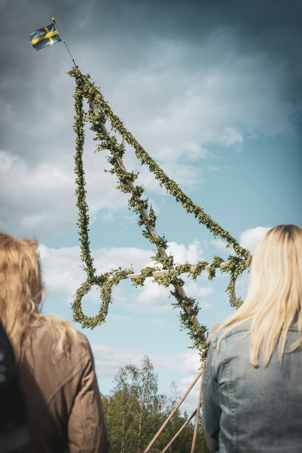 two women standing facing flag on pole