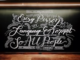 Intricate chalkboard art with elaborate, cursive text and decorative floral elements. The design emphasizes accessibility of messages across languages and formats.