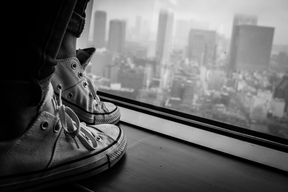 person standing near a window greyscale photography