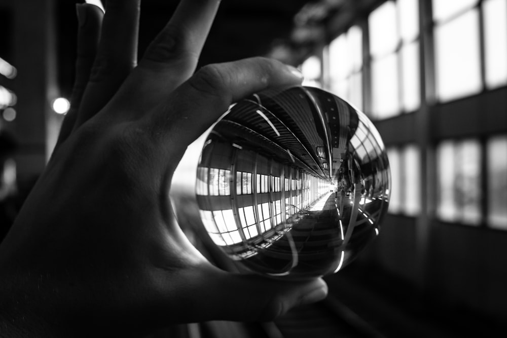 person holding a sphere clear glass close-up photography