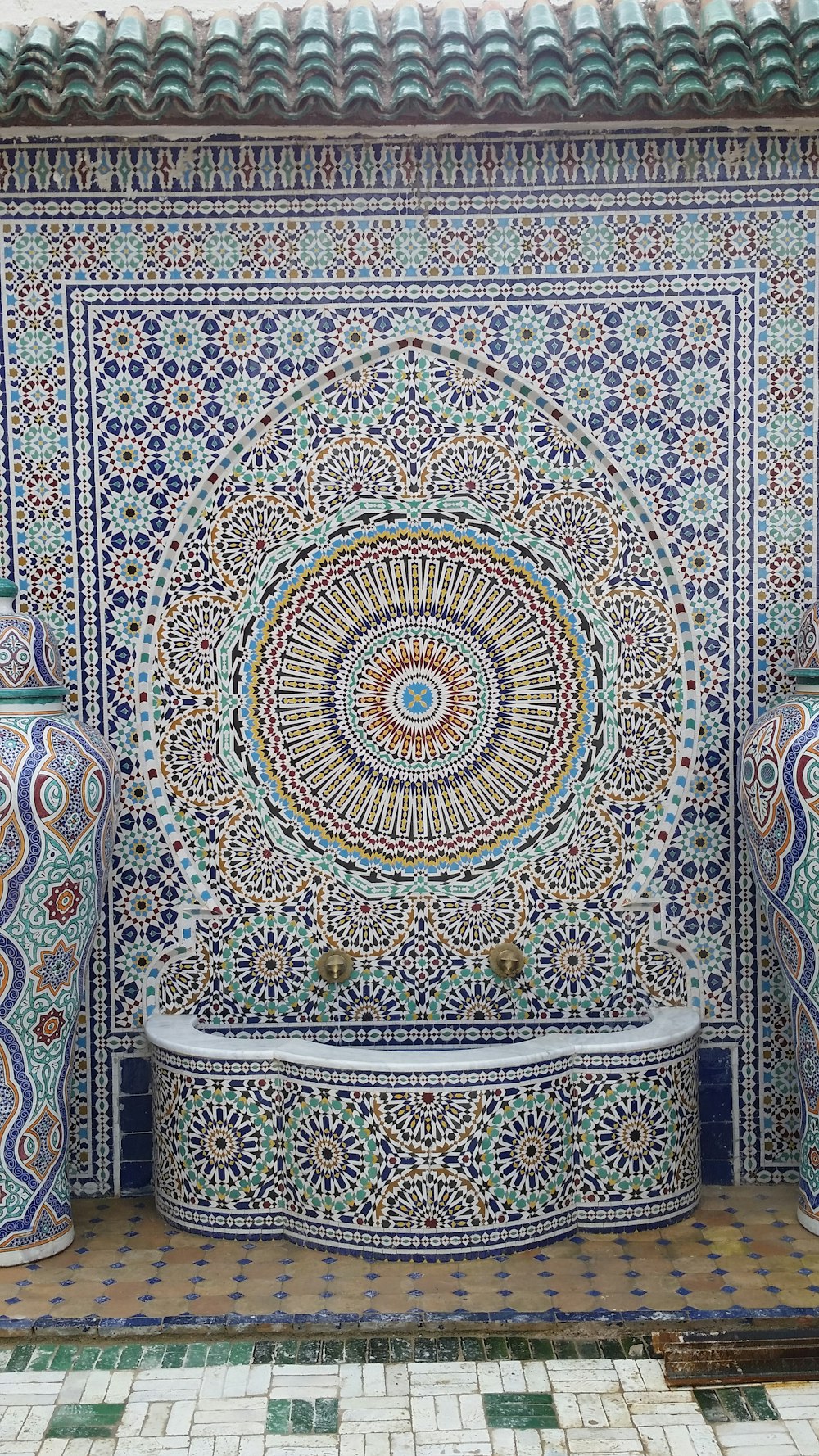 white, blue, and brown floral tiled fountain outside of building