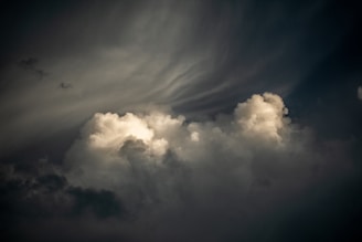 Dramatic and dark clouds fill the sky, with the top edges illuminated, creating a contrasting effect between light and shadow. The swirling pattern in the atmosphere suggests movement, adding a sense of depth and dynamism.