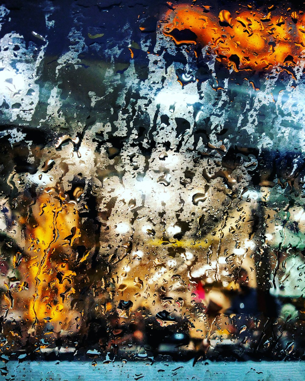 una vista di una strada attraverso una finestra coperta di pioggia