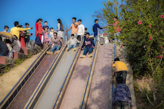 Families enjoying a sunny day at the park with children playing on the roller slide.