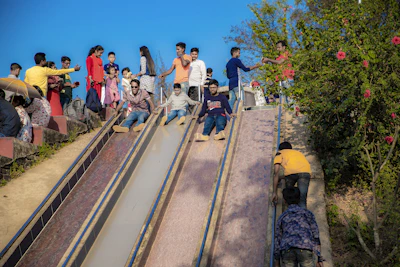 Families enjoying a sunny day at the park with children playing on the roller slide.