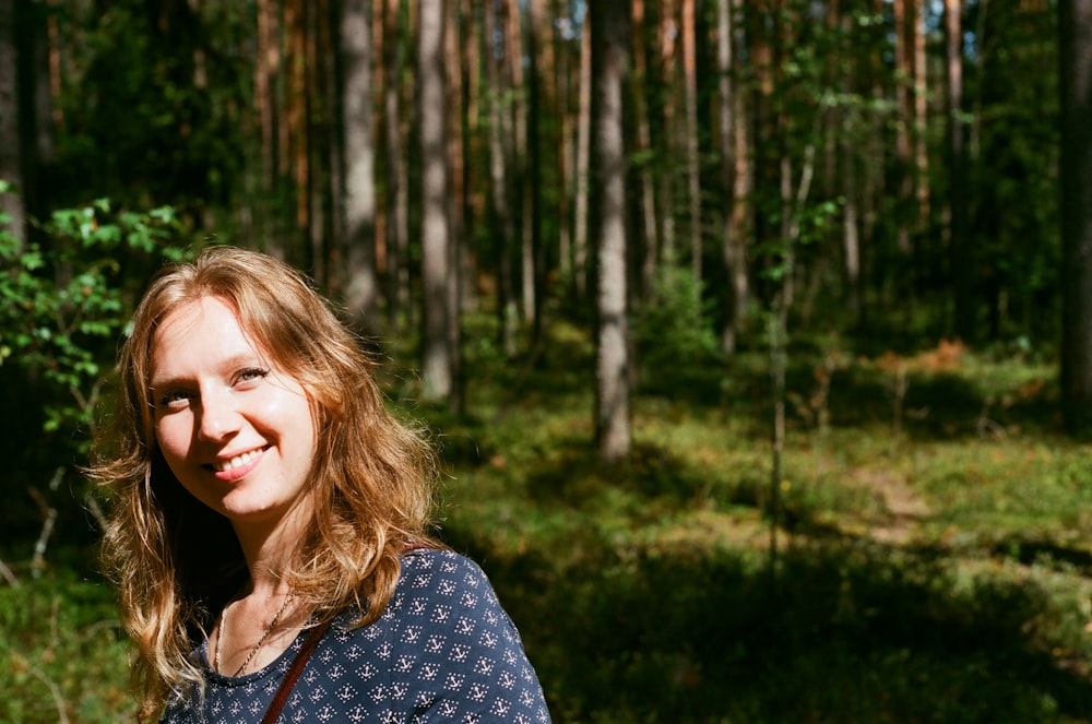 Frau steht auf Wald und lächelt