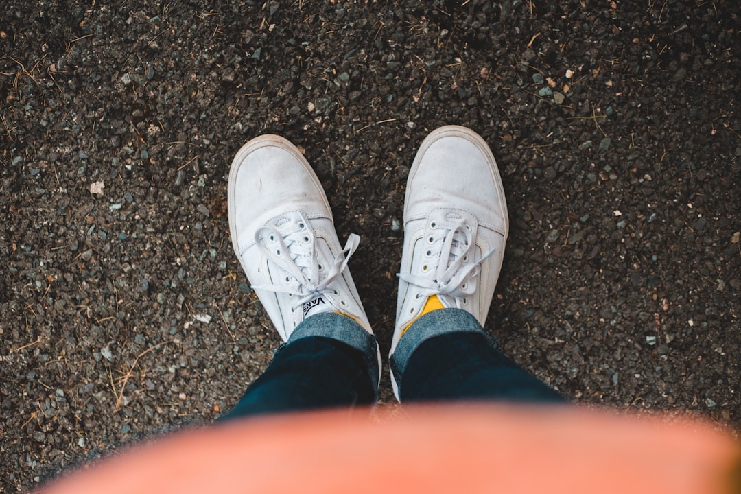 person wearing blue jeans and white shoes close-up photography