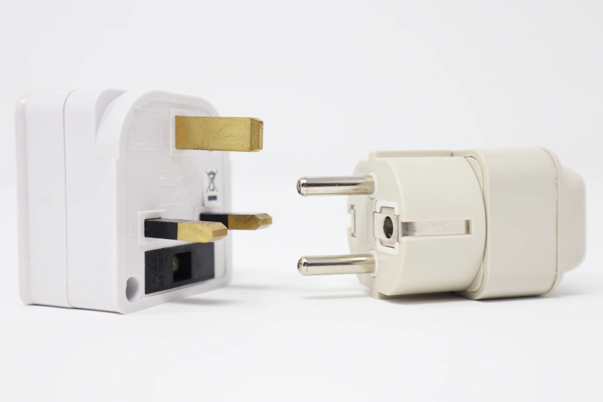 Two different electrical adapters lying side by side on a plain background