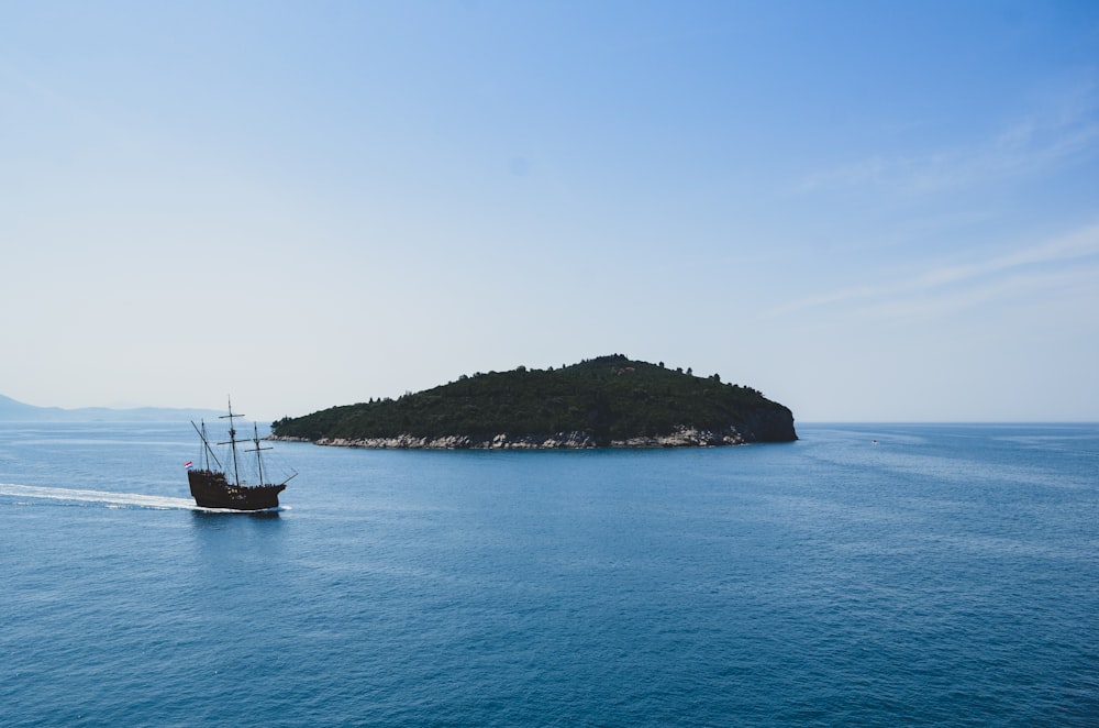 boat in a body of water near a island during daytime