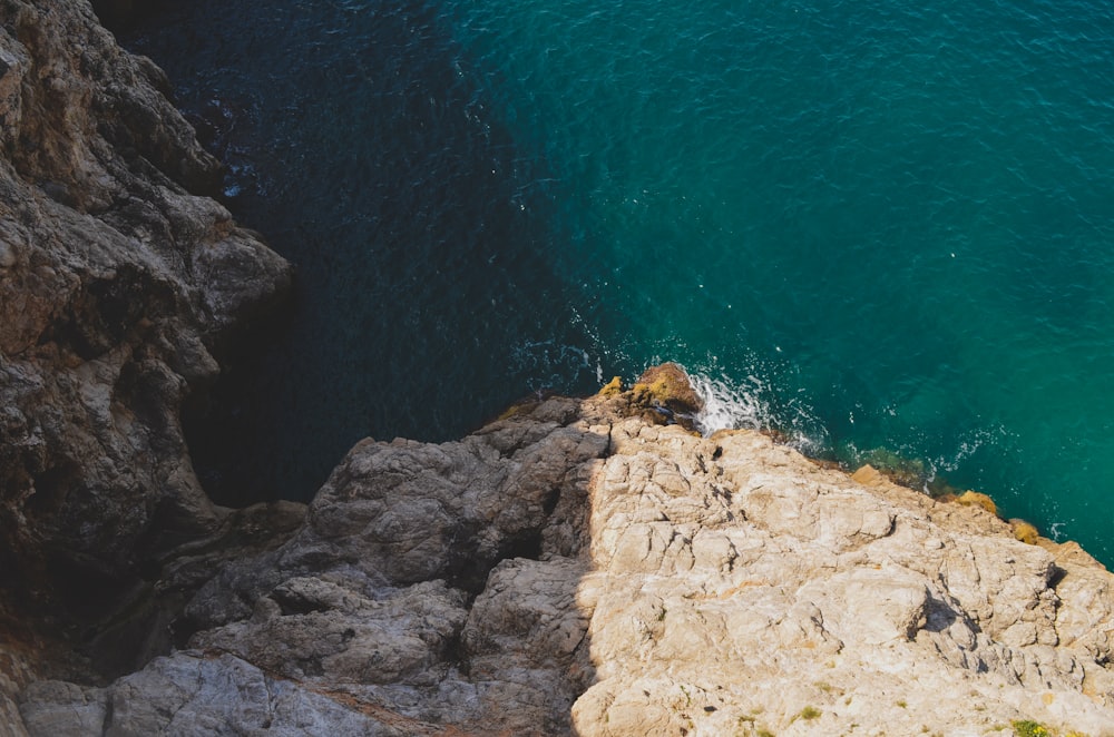 an aerial view of a rocky cliff and a body of water