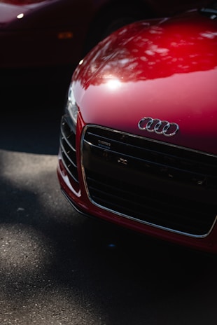 Close-up shot of a bold red Audi grille with reflective chrome accents under natural light.