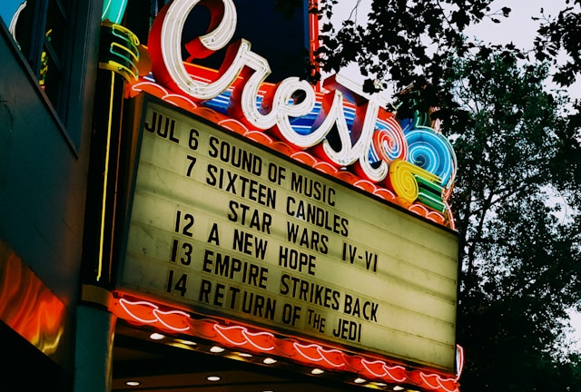 A vintage cinema marquee lit up at dusk with movie titles.