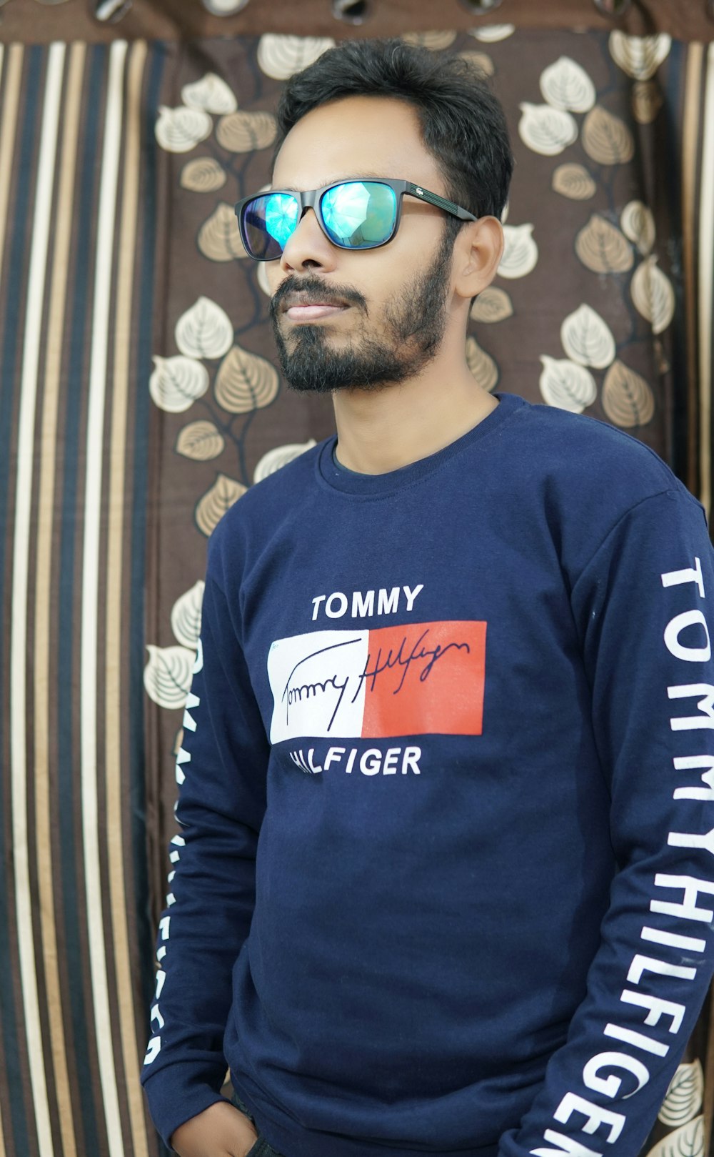 a man wearing a tommy hiiger sweater and sunglasses