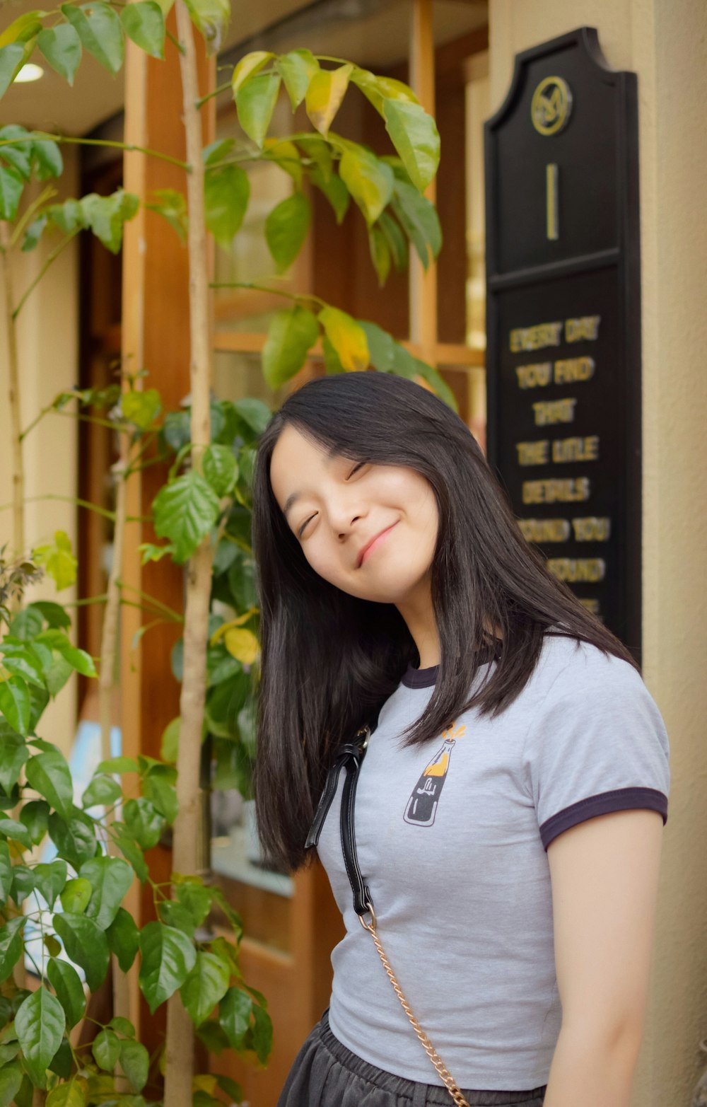 a woman standing in front of a green plant