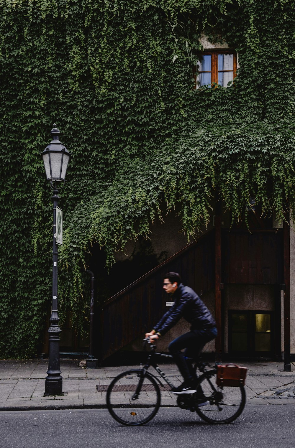 hommes conduisant un vélo près de la maison et du lampadaire pendant la journée
