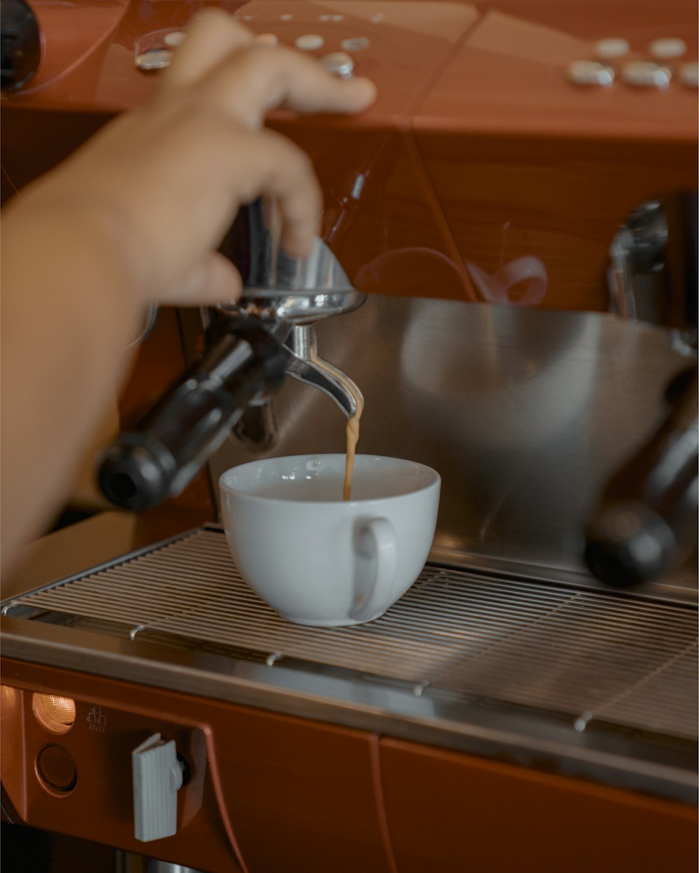 a cup of coffee being poured into a coffee machine