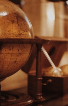 A vintage globe resting beside an open ancient manuscript, bathed in warm sunlight.