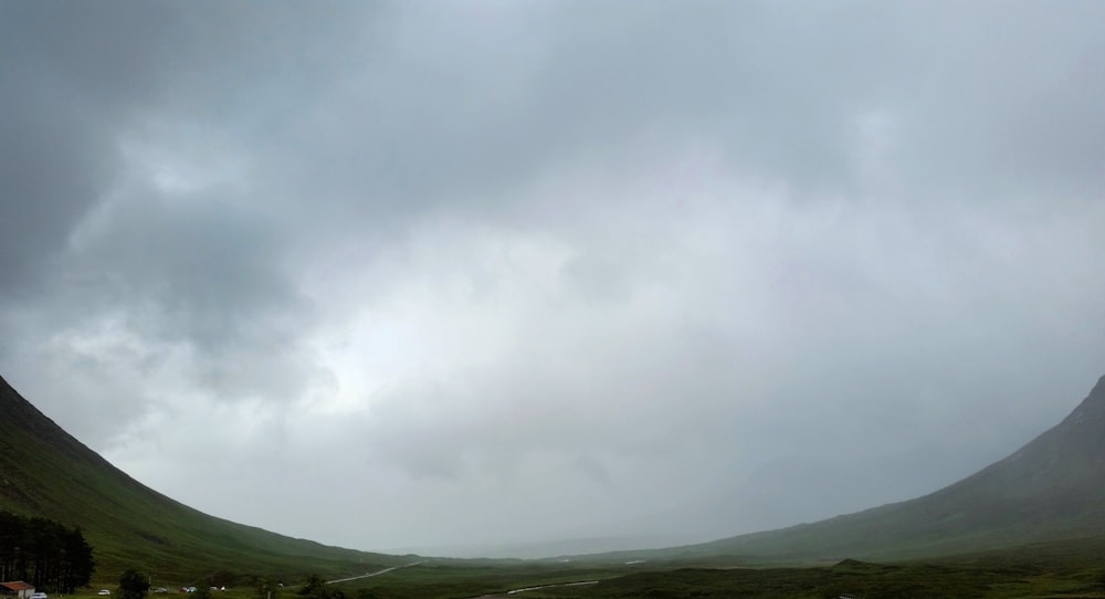 a road in the middle of a mountain range under a cloudy sky