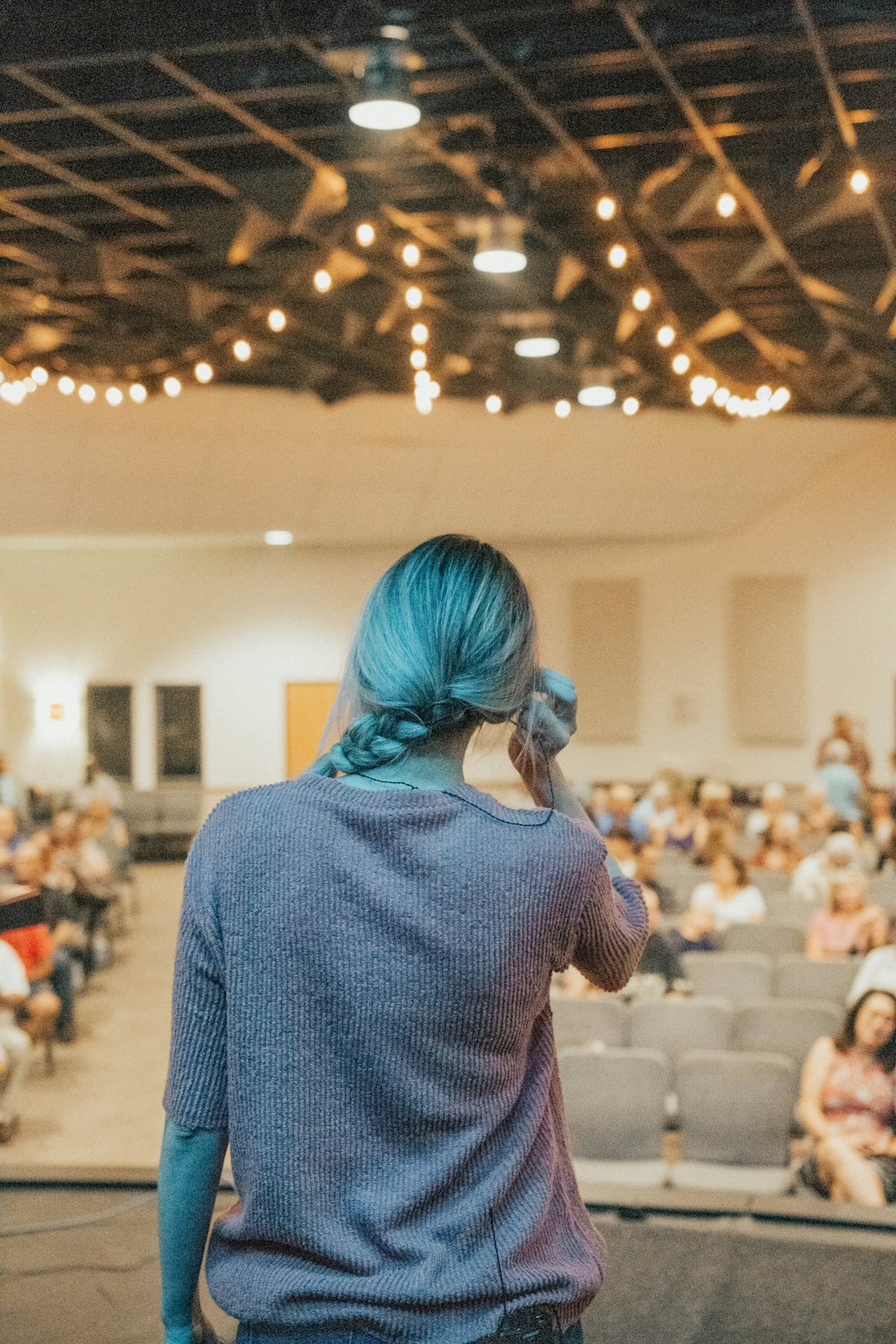 a woman with blue hair standing in front of an audience