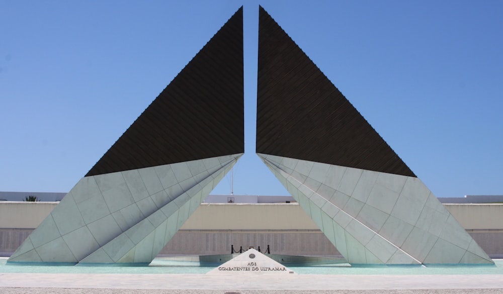 triangular black and gray concrete archway under calm blue sky