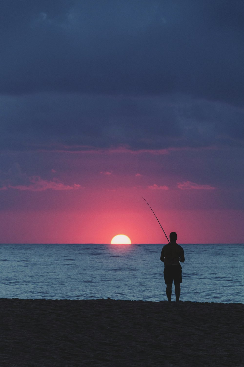 silhouette photography of man fishing in the sea during golden hour