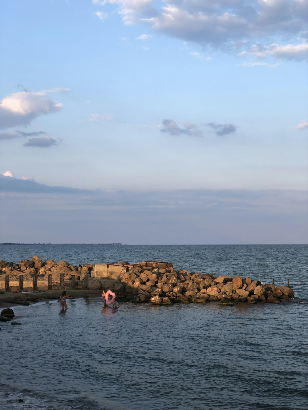 people in sea near boulders