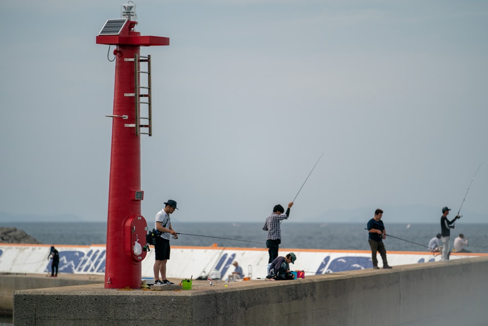 Pessoas pescando perto de uma torre vermelha durante o dia