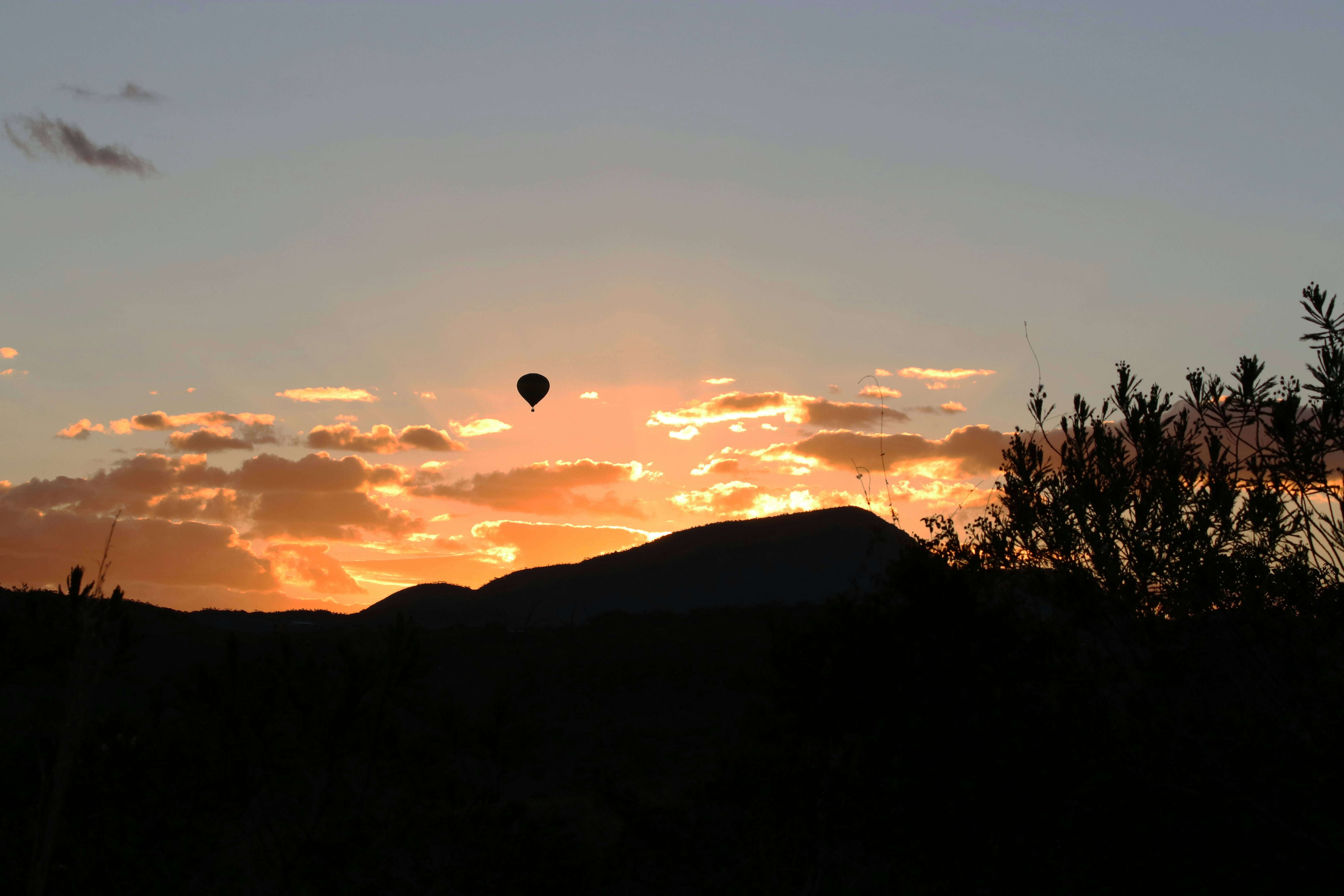 a hot air balloon flying in the sky at sunset