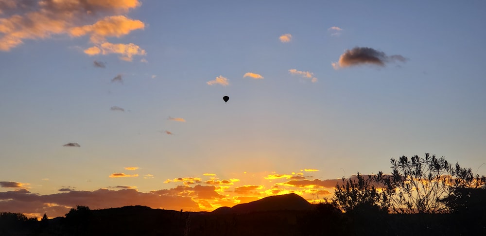 a hot air balloon flying in the sky at sunset