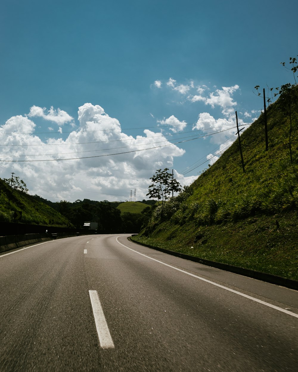 green hill near road during daytime