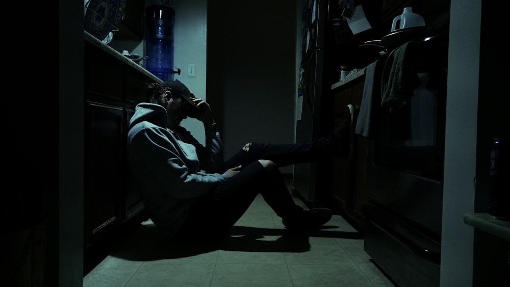 a man sitting on the floor in a dark kitchen