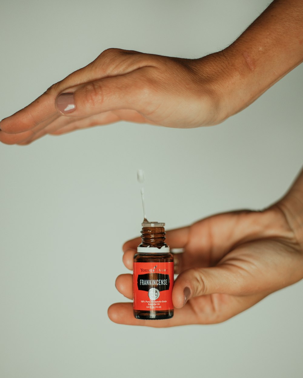 person holding red and black labeled bottle