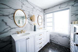 Bright marble and gold bathroom with two sinks and two mirrors.