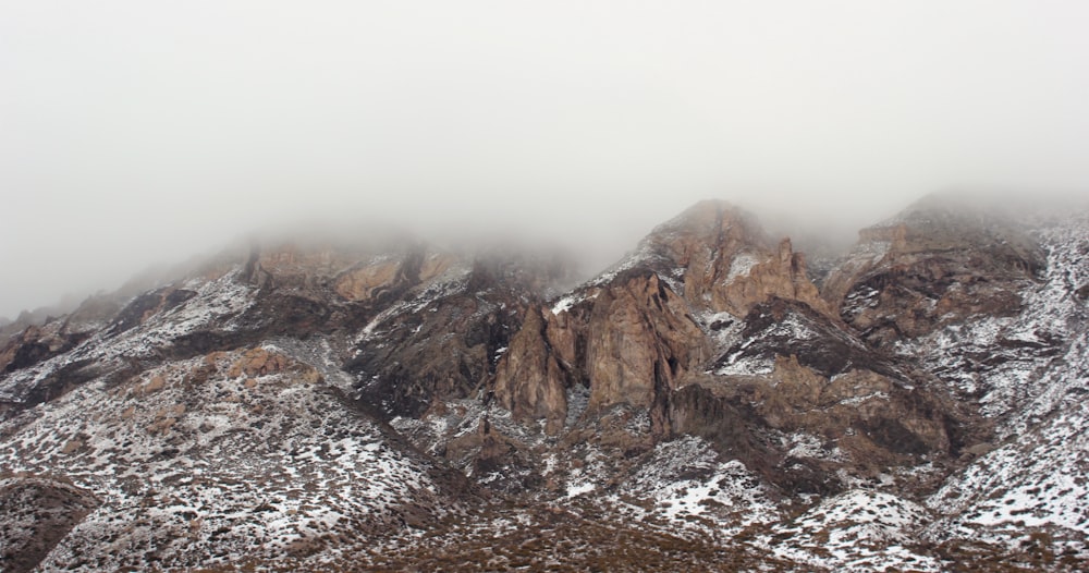 snow covered mountain with clouds forming