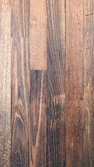 Dark wooden planks with visible grain patterns and some knots create a rustic and textured surface. The wood has various shades of brown, ranging from light to dark tones, adding depth and character.