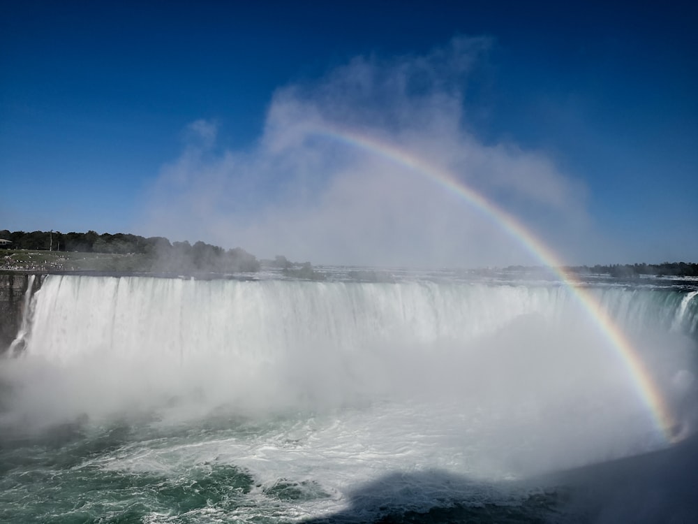 rainbow forming above waterfalls