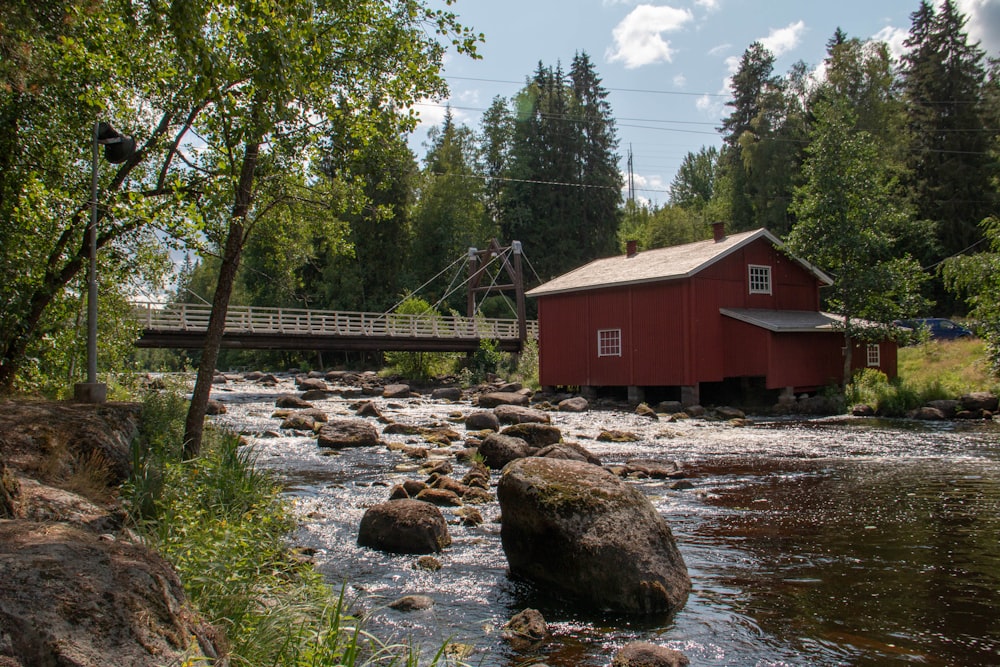 red wooden house along the river near grey bridge