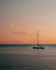 black yacht anchored at sea during sunset