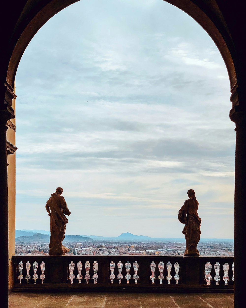 two statues on balcony railing during day