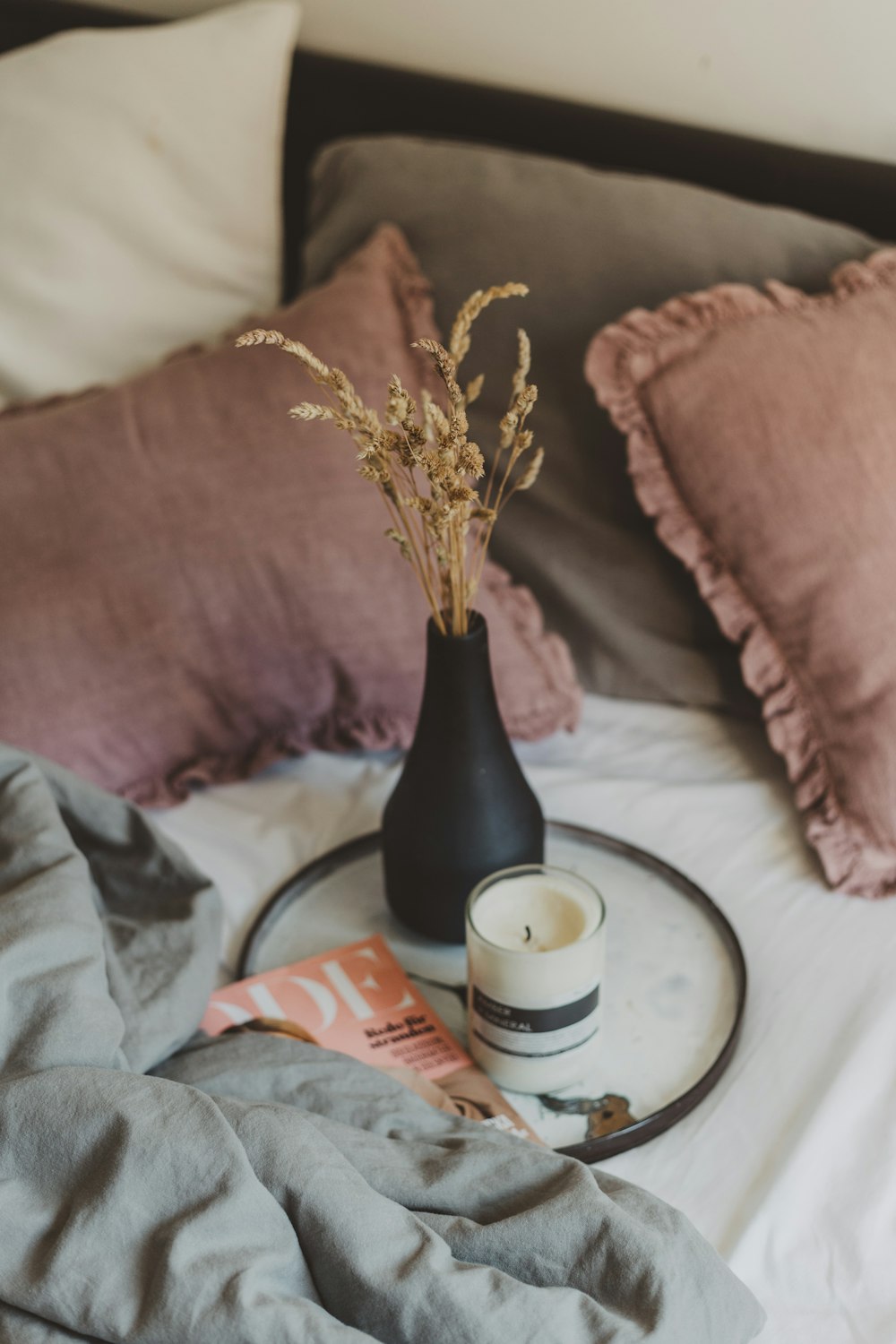 white candle beside brown vase on tray