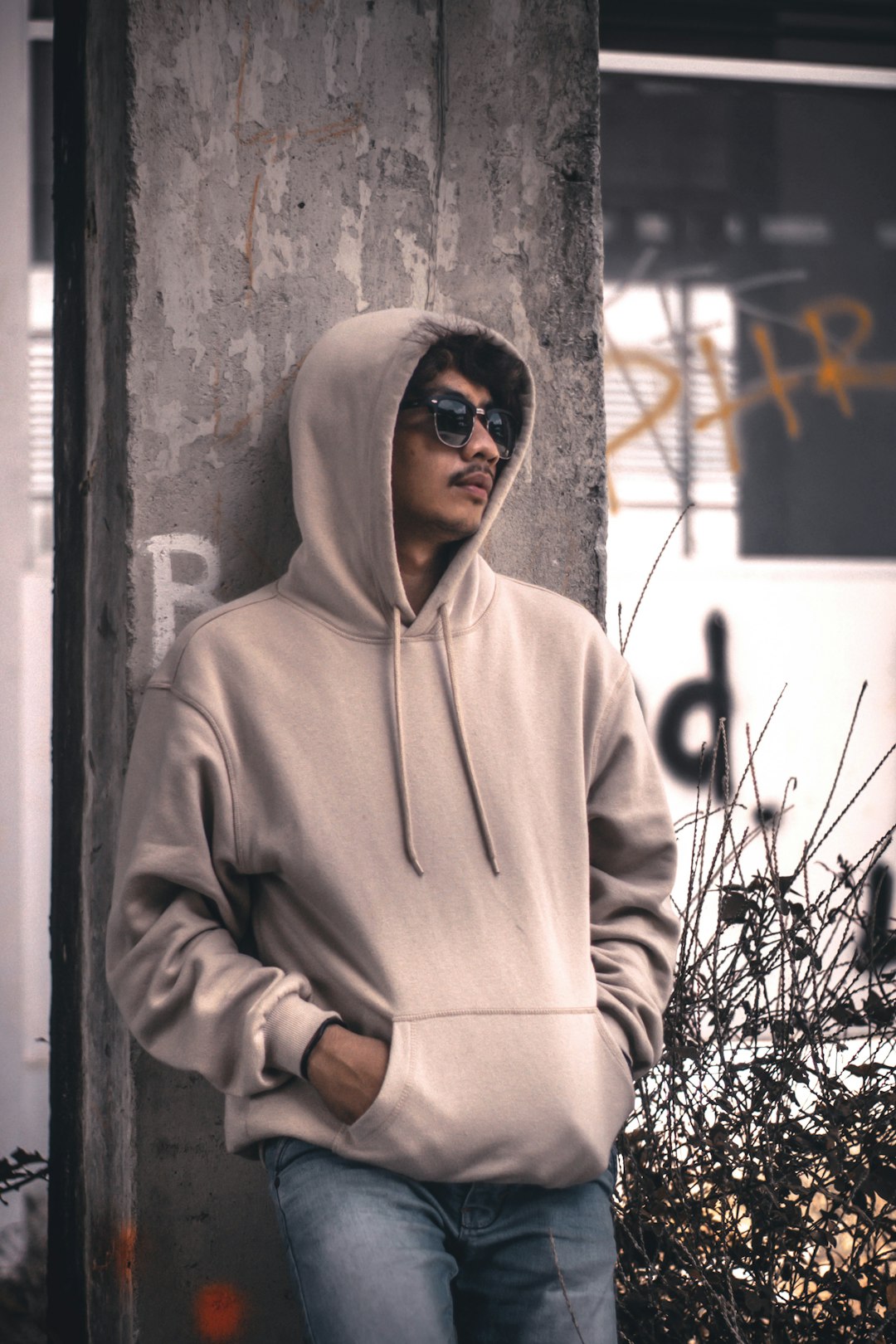 men wearing a grey hoodie jacket leaning in a wall during daytime