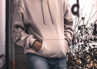 men wearing a grey hoodie jacket leaning in a wall during daytime