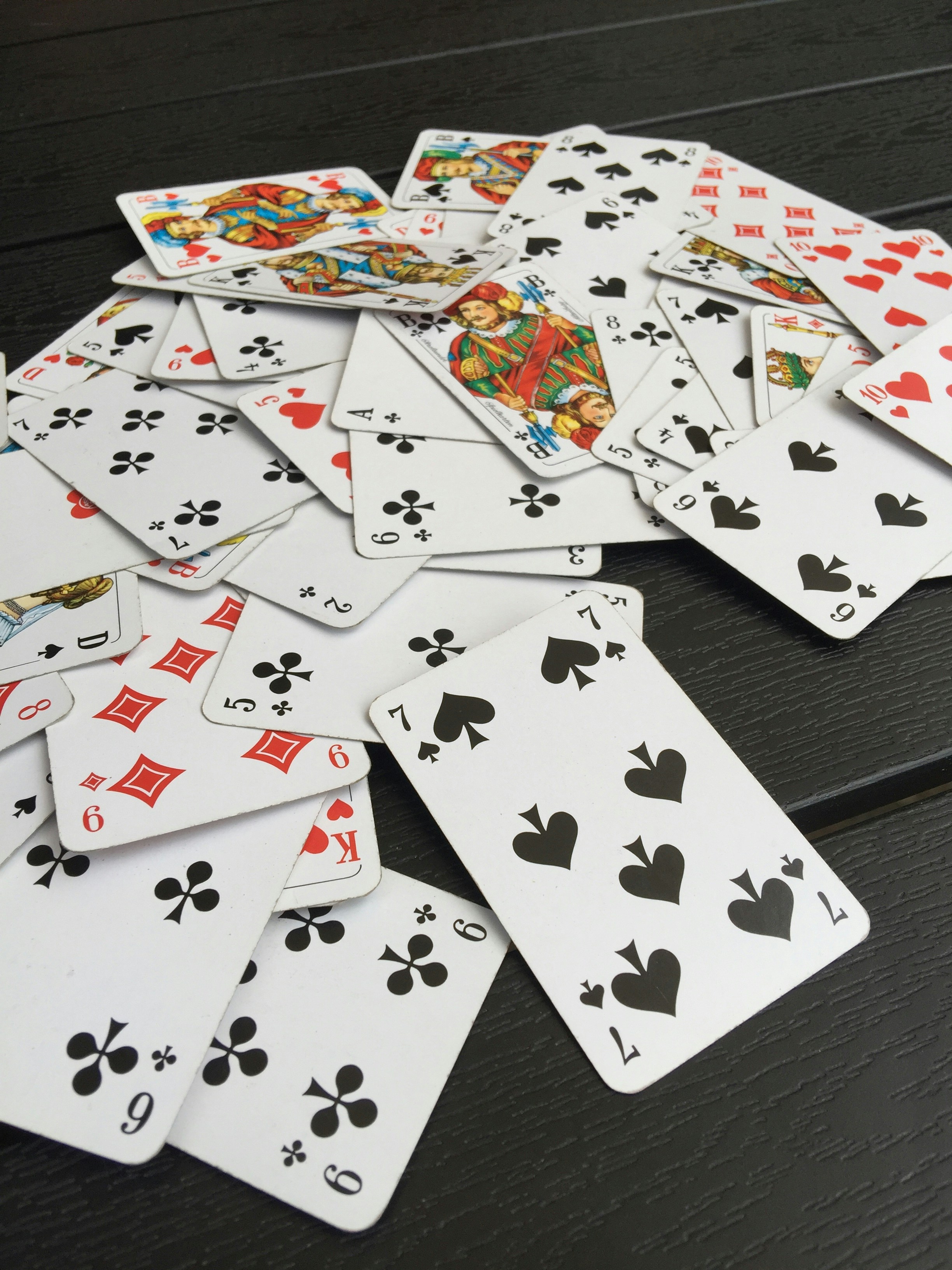 Colorful playing cards spread on dark table, moody dim lighting, deep shadows