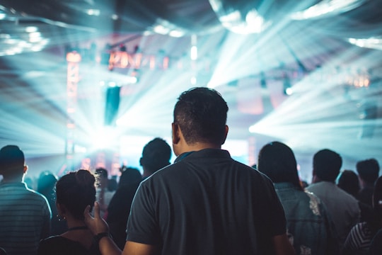 A dazzling crowd at a night entertainment event under red and gold lights.