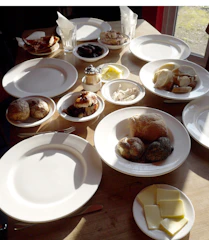 Breakfast setup with fresh bread, local cheeses, and seasonal fruits on a wooden table.