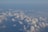 A vast expanse of soft, fluffy clouds viewed from above, merging with a clear, light blue sky. The light subtly highlights the cloud contours, creating a serene and tranquil atmosphere.