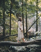 Claudia walking barefoot on a forest path surrounded by tall trees and natural light.