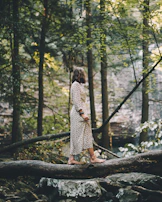 A quiet morning scene with a woman in a long dress walking barefoot on a wooden porch, soft light casting gentle shadows.
