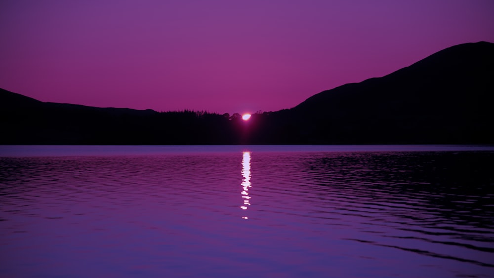 Foto da paisagem violeta e preta de um pôr do sol em um lago