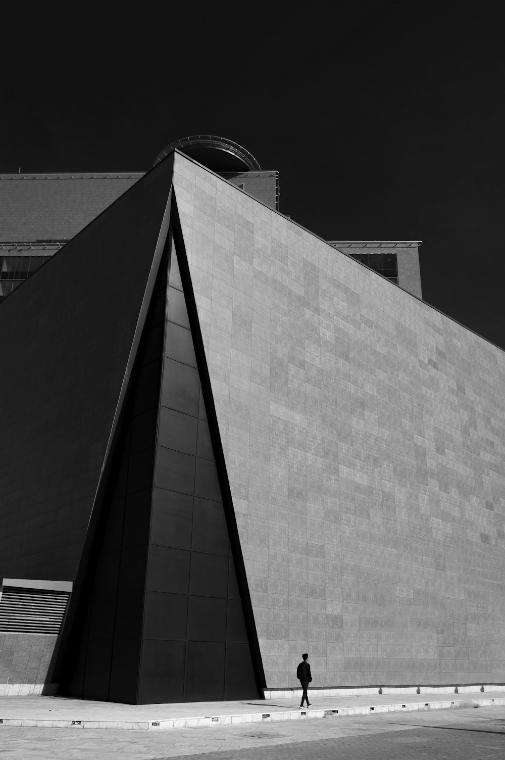 a black and white photo of a person walking in front of a building